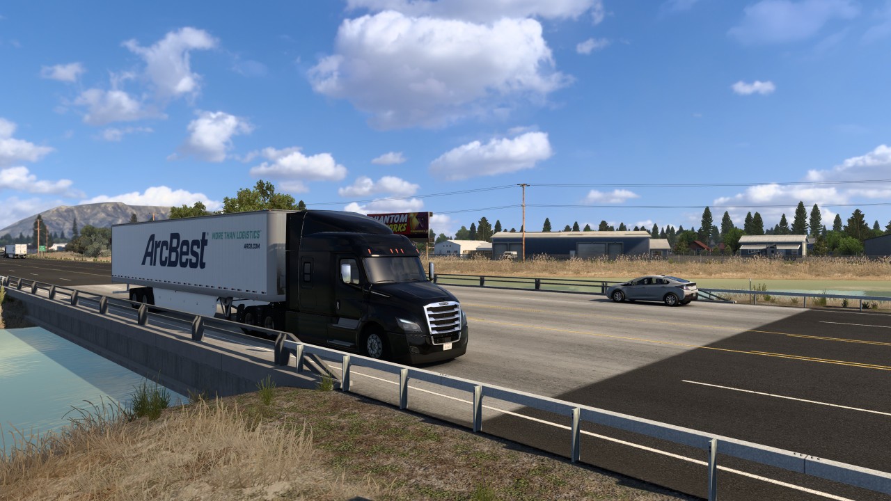 Ein schwarzer US-Lkw mit weißem Trailer fährt über eine Brücke.